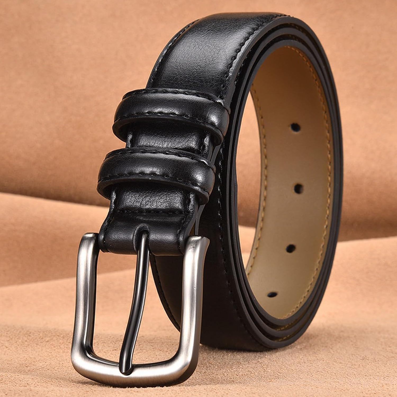 Black leather belt with silver buckle on a beige background
